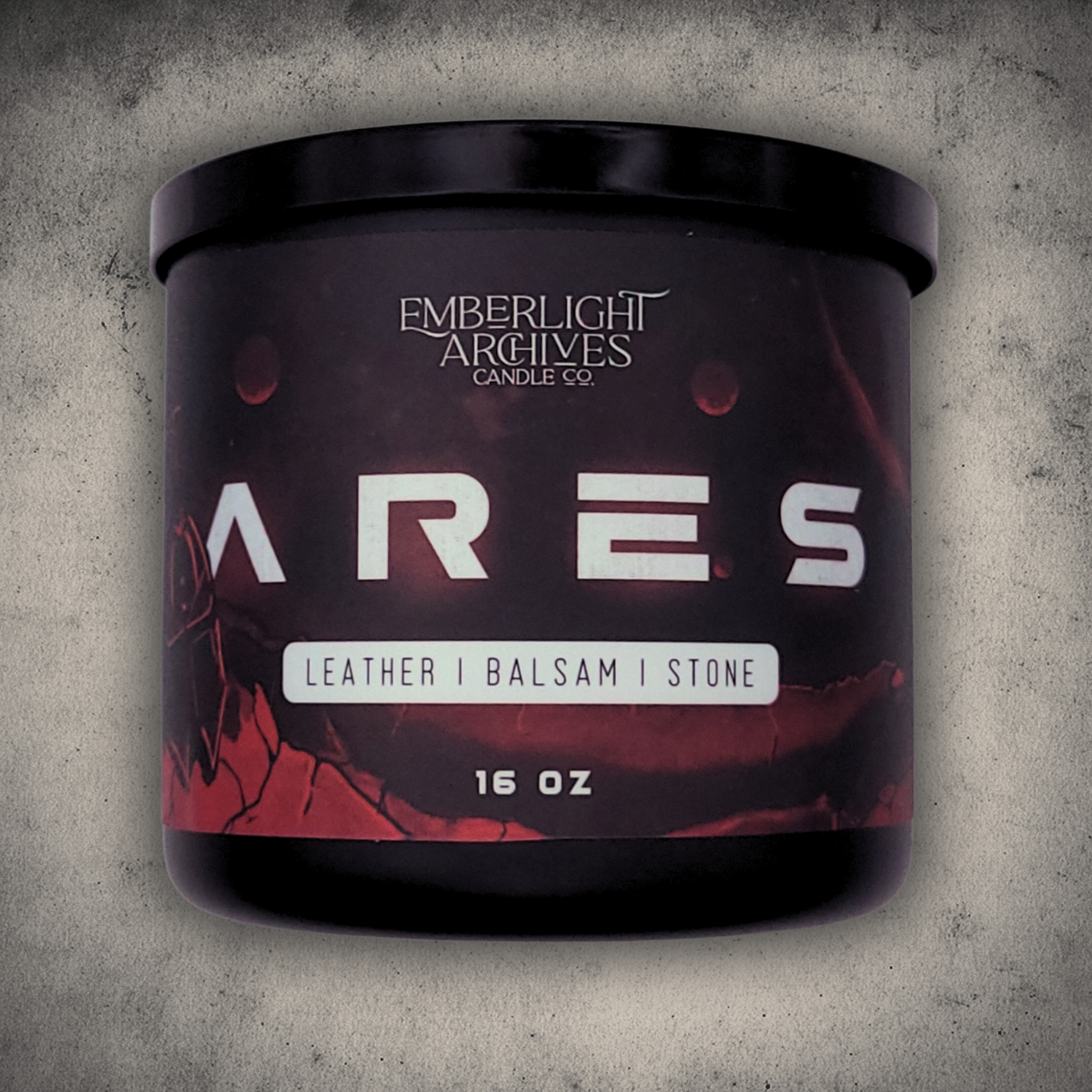 Emberlight Archives Ares candle in a 16oz black glass jar with illustrated red planet label against a gray stone background, Leather & Balsam scent.